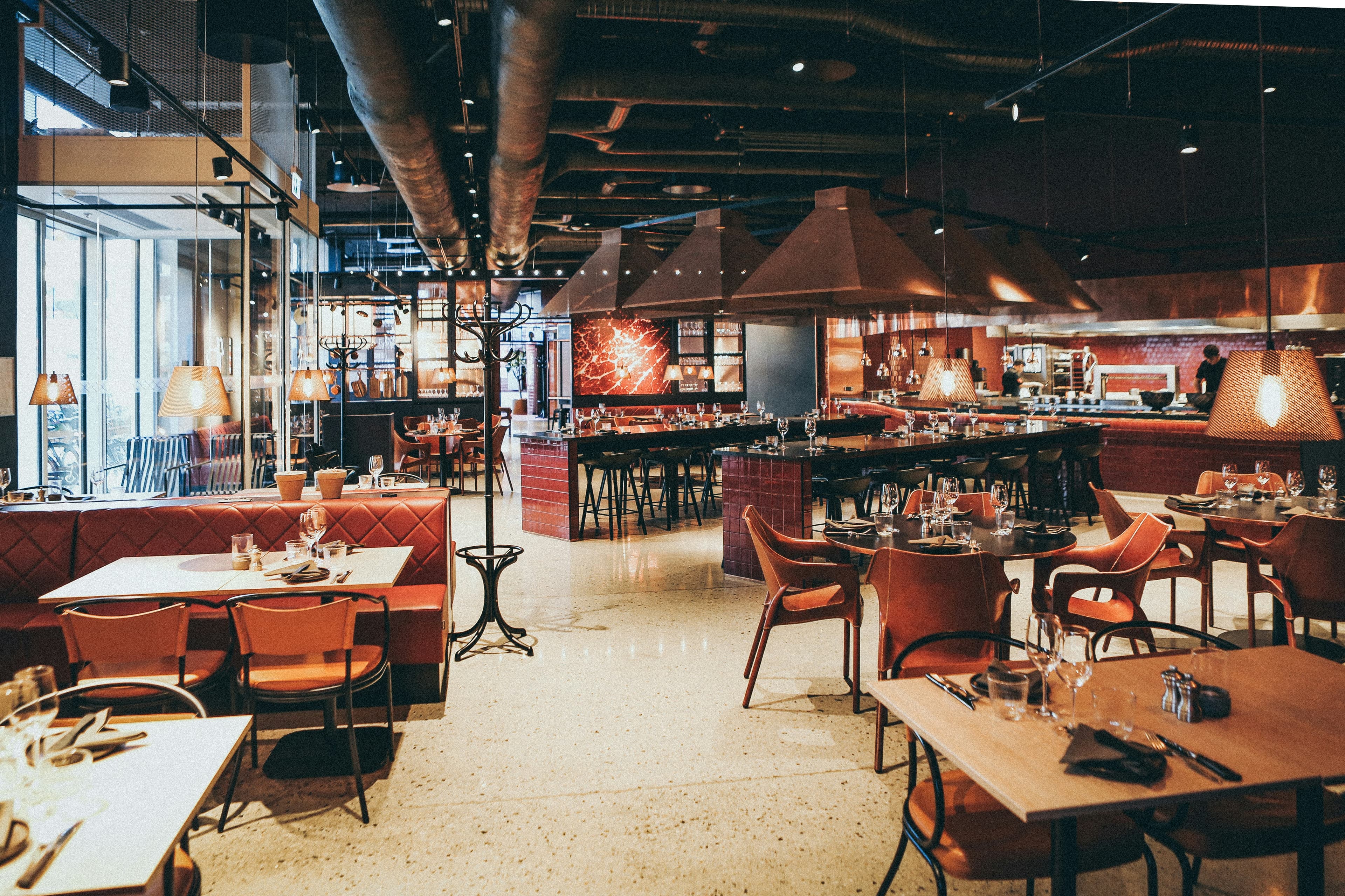 A warm restaurant dining room with booths and hanging lights